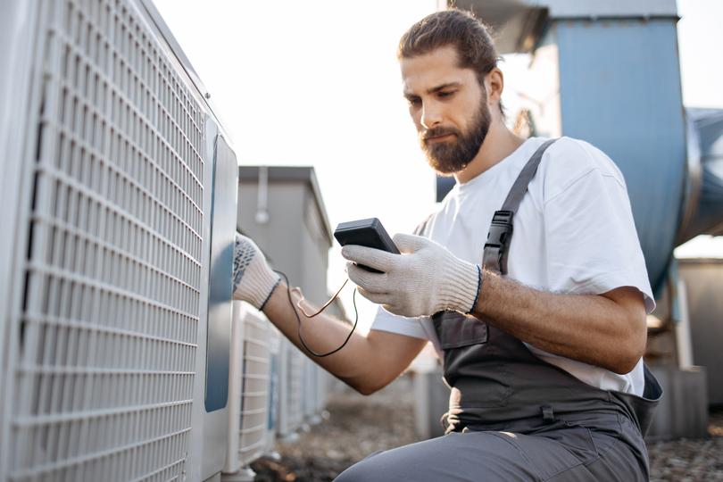 An HVAC technician servicing an air conditioning unit